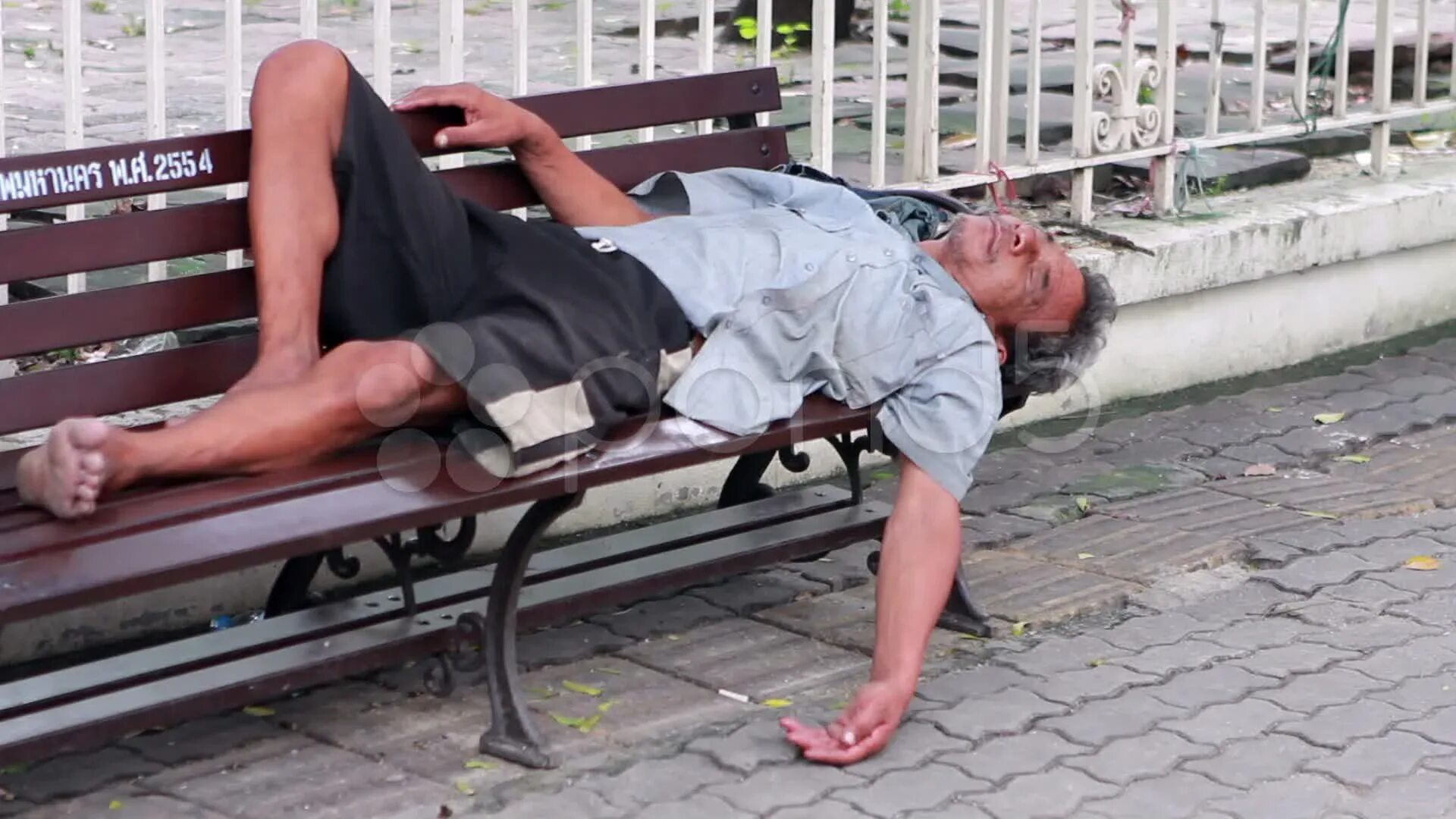 Мужчина лежит на улице. Спящий бомж на скамейке.