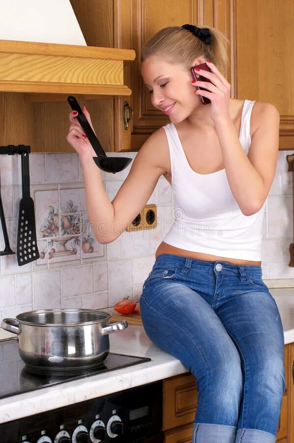 Сядь на кухне. Фотосессия на кухне в джинсах. Девушка в джинсах на кухне. Женщина на кухне в майке. Девушка готовит.
