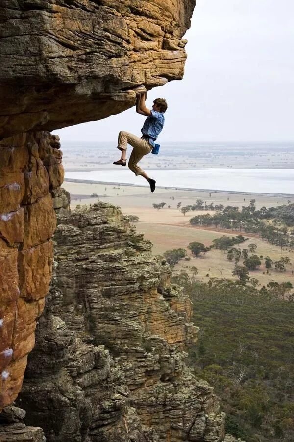 Самые опасные увлечения. Человек висит на скале. Человек на скале. Скалолаз. Скалолаз на скале.