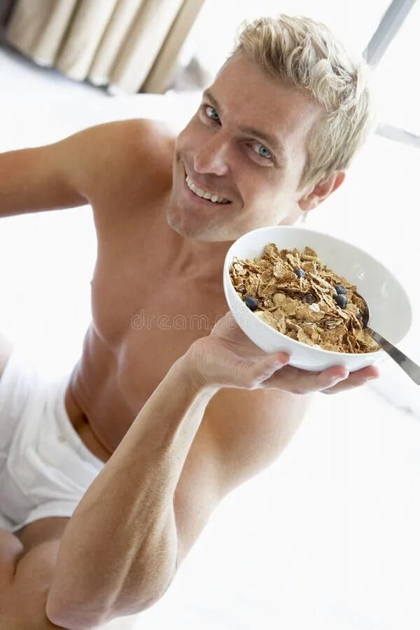 Человек есть гречку. Мужчина с тарелкой. Парень ест хлопья. Мужчина завтракает. Человек ест сухой завтрак.
