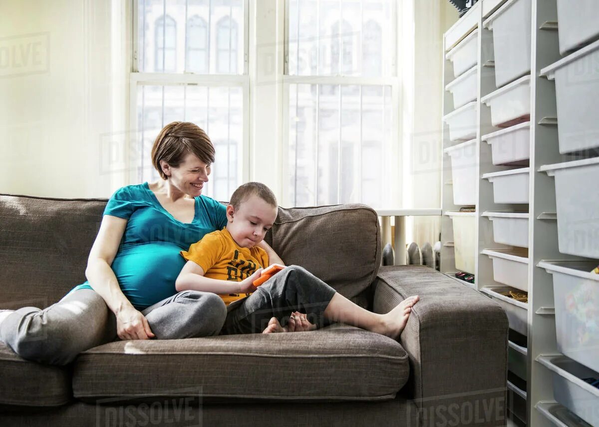 Mother and son on Sofa. Portrait of mother and her son on Sofa at Home - stock photo. Mother sit on son. Mother Lies on Sofa.