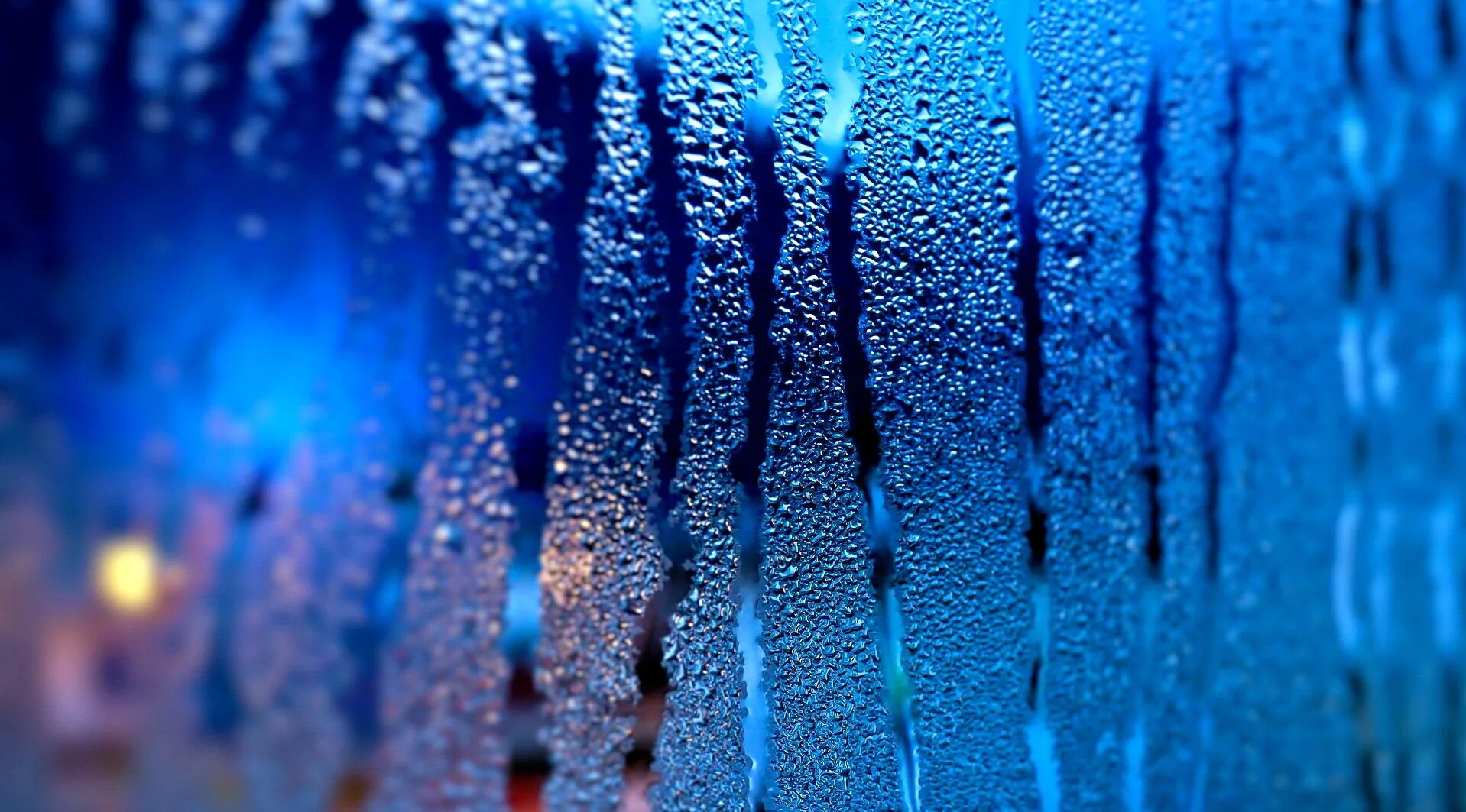 Капли дождя в воздухе. Капли на стекле. Синий дождь. Текстура стекла. Мокрое стекло.