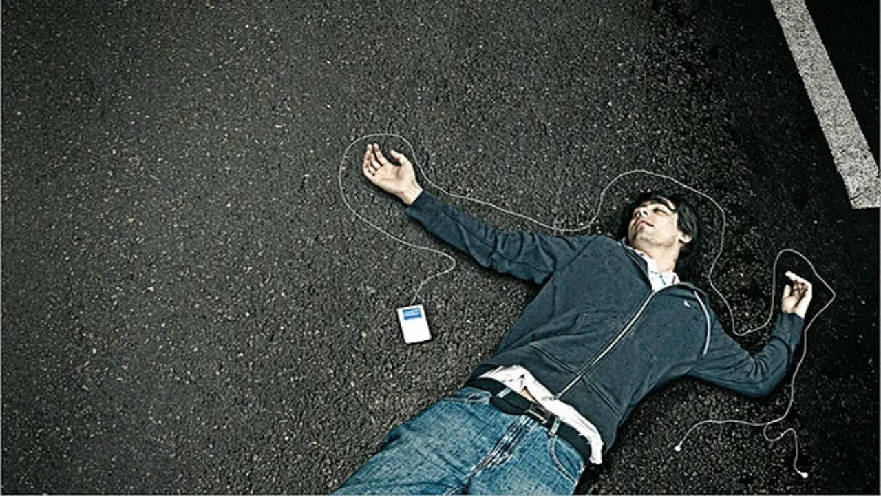 Мужчина лежит на улице. Парень лежит на асфальте.