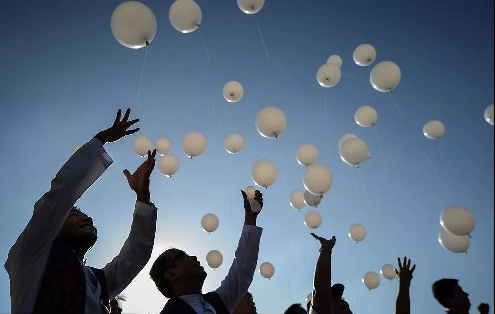 Выпустили в небо шары. Толпа с шарами воздушными. Люди запускают шары. Белые шарики в небе. Выпускники с белыми шарами.