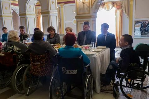 Старый инвалид сидя на столе нашивал синюю