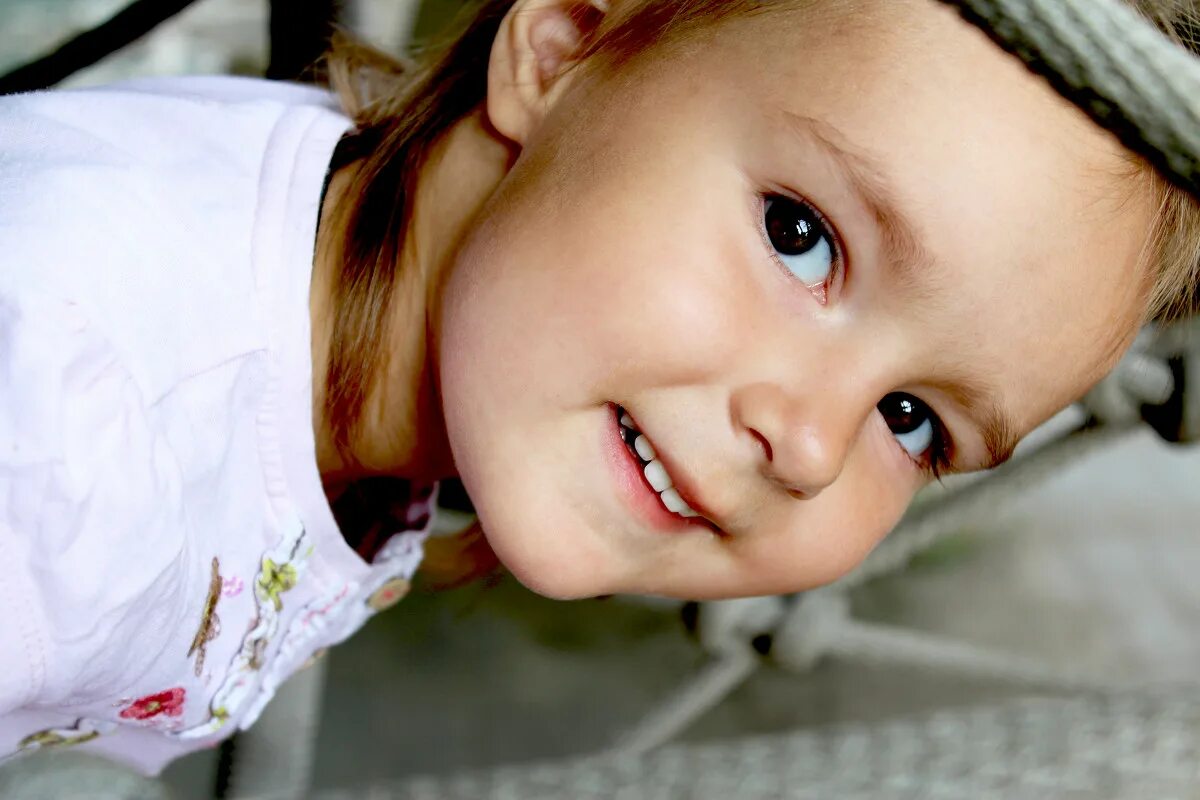 В его улыбке было что то детское. Радостное лицо ребенка. Счастливые улыбки детей. Девочка с кудрявыми волосами. Веселые дети.