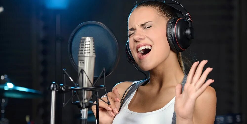 Частные уроки вокала в москве. Девушка поет в студии. Студия вокала. Девушка в студии звукозаписи. Поет в микрофон.