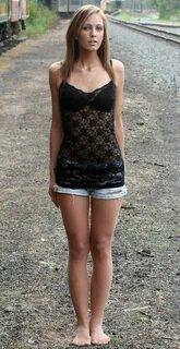 Pretty young woman in her suntan pantyhose and daisy duke shorts by the rai...