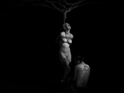A black and white image of a nude woman performing the Japanese bondage art...