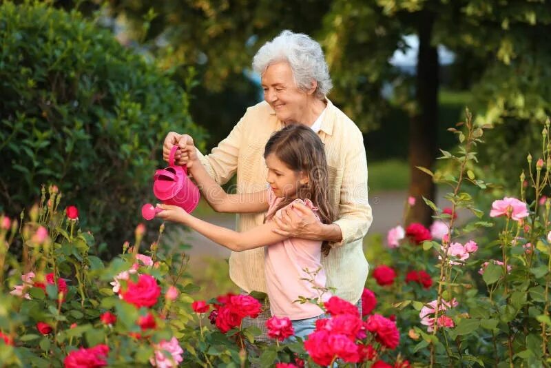 Mother is watering the flowers now. Мама с дочкой поливают цветы в саду. Девочка с лейкой. Дети собирают травы. Mother is watering the flowers now.