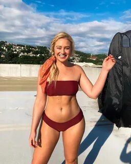 Iskra Lawrence posing outside in a red bikini looking fit.