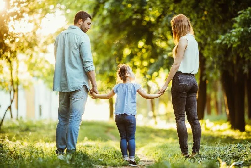 Счастливая семья на прогулке. Дети с родителями в парке. Родители с ребенком за руку. Прогулка с семьёй с дочкой. Дочка в папу пошла