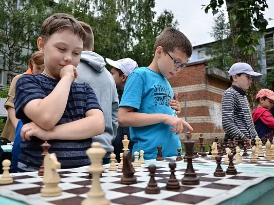 Два друга играли в шахматы. Шахматы во дворе. ребенок радуется в шахматах. шахматный турнир. шахматный турнир на улице.