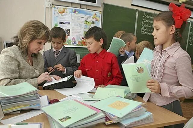 Родной язык в школе урок. Учитель раздает тетради. Учитель с тетрадями. Учитель проверяет тетради. Ученик сдает учителю тетрадь.