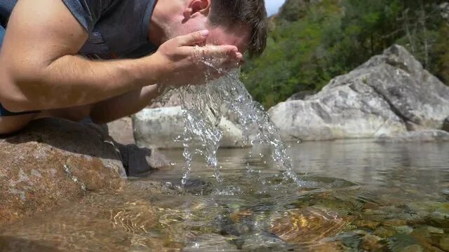 Умывается в реке. Умывание в реке. Человек пьет воду из ручья. Пить из ручья.