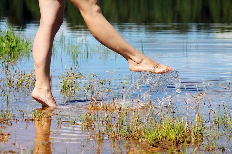 Дерево ногами в воде. "Гуляющая вода". Морщатся ноги в воде. Девочка плескается в воде ногами передний план. Гуляют на пляже ноги в воде.