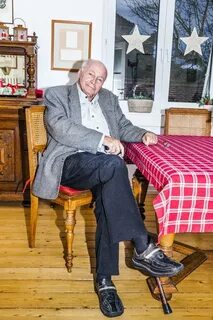 Старый инвалид сидя на столе нашивал