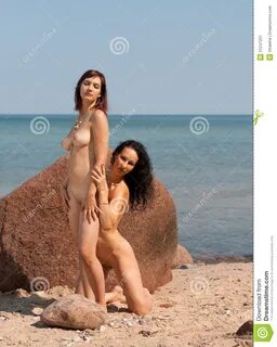 Dos mujeres desnudas jovenes que toman el sol en la playa.