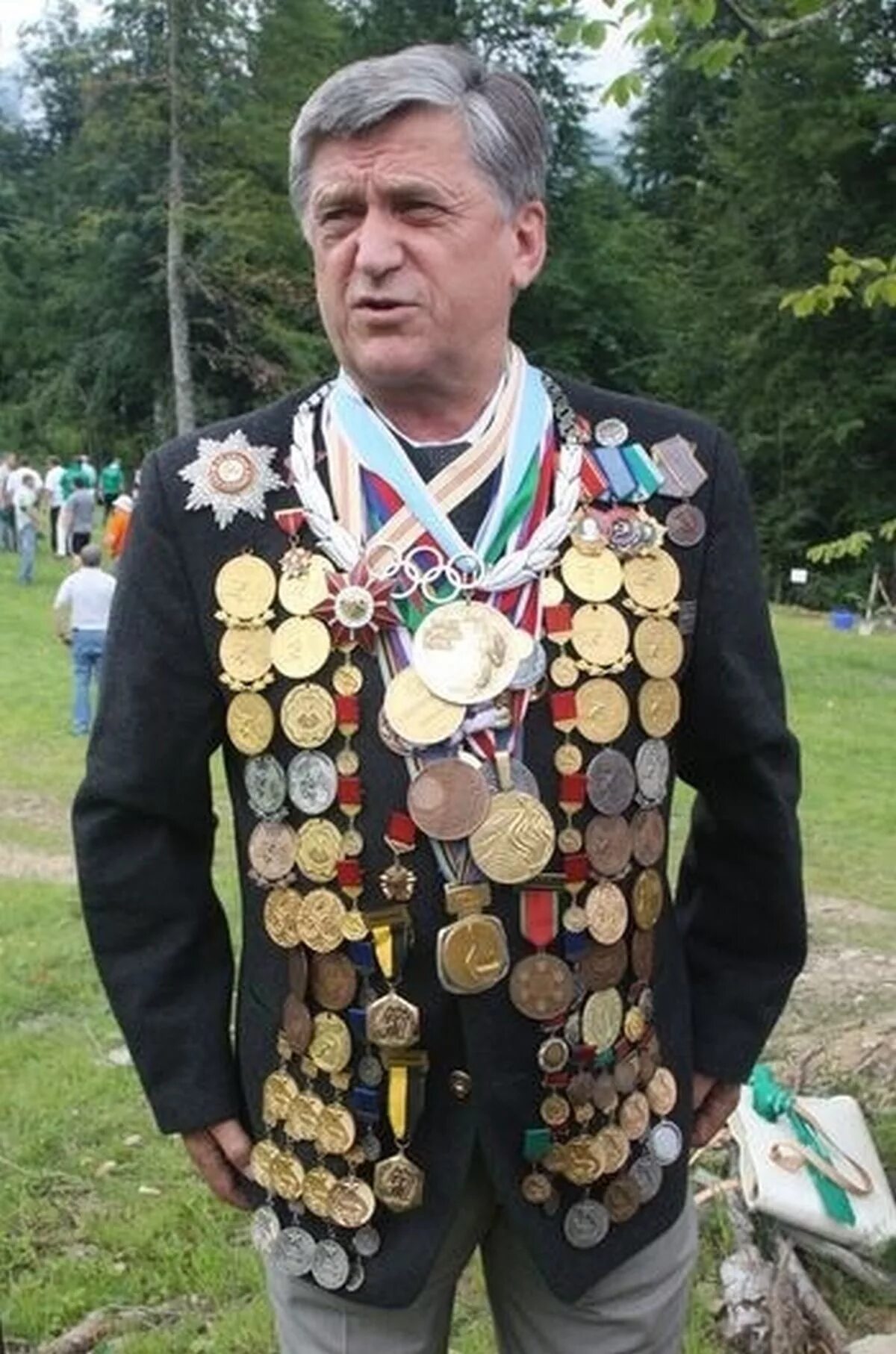 Человек с кучей медалей. Очень много медалей. Медали на пиджаке.