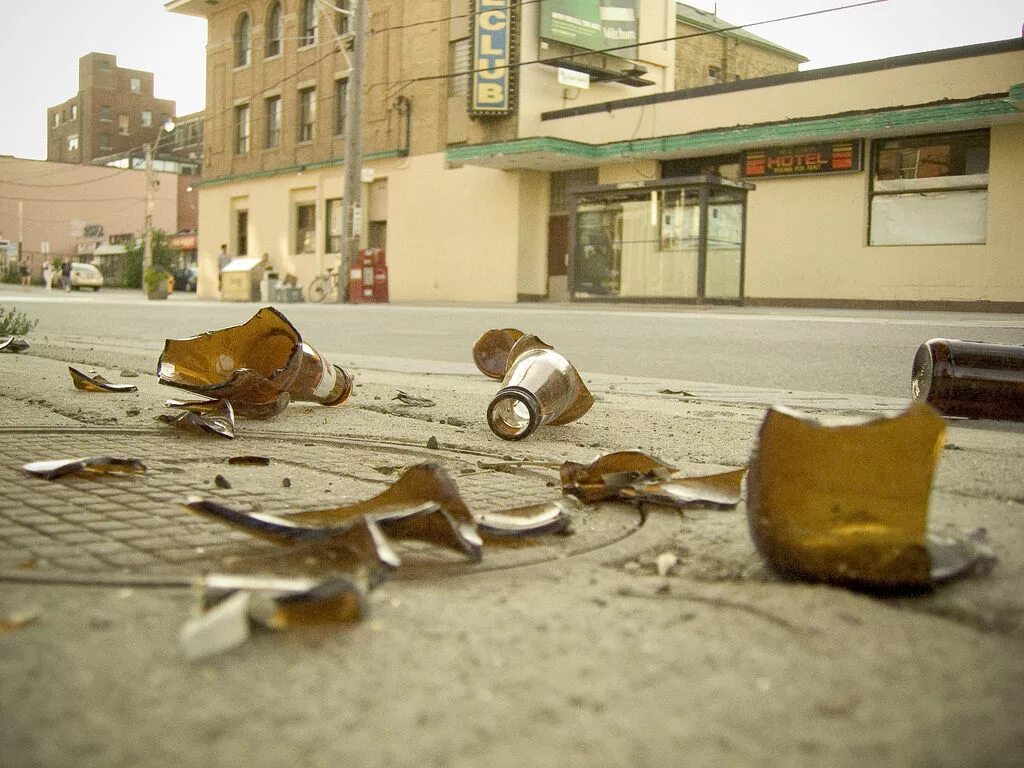 Разбивание бутылки. Разбитая бутылка на тротуаре. Фотография разбитой бутылки.