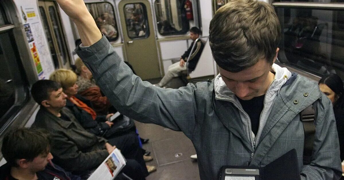 Проходить в метро по телефону. Чтение в метро. мужчина в метро с телефоном. человек с книгой в метро. человек с книгой в транспорте.
