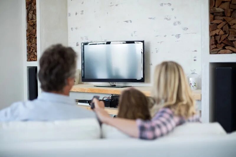 Tv in our life. Семья смотрит телевизор. Папа с дочкой смотрят телевизор. Люди уставились в телевизор.