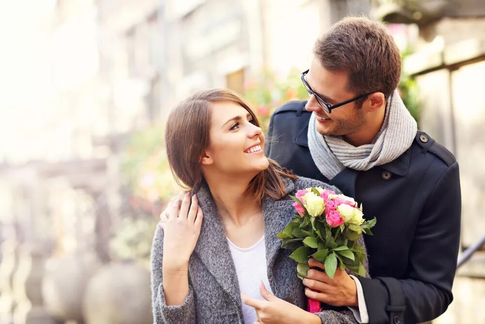 Парень дарит девушке цветы. Мужчина дарит цветы женщине. Влюбленные весной. Мужчина и женщина с цветами.