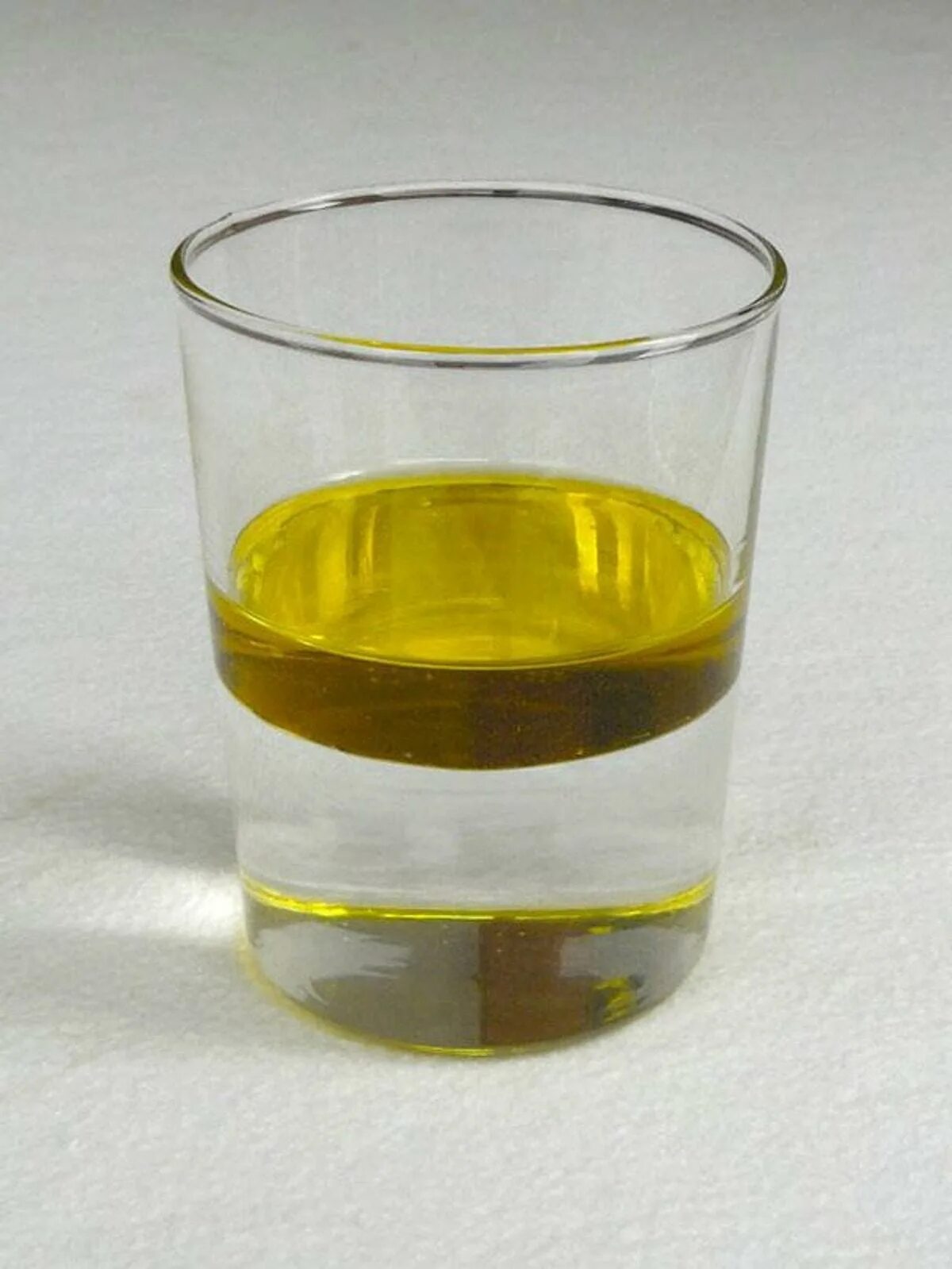 В стакане налито подсолнечное масло. Растительное масло в стакане. Масло и вода в стакане. Смесь растительного масла и воды. Смешивание воды и растительного масла.