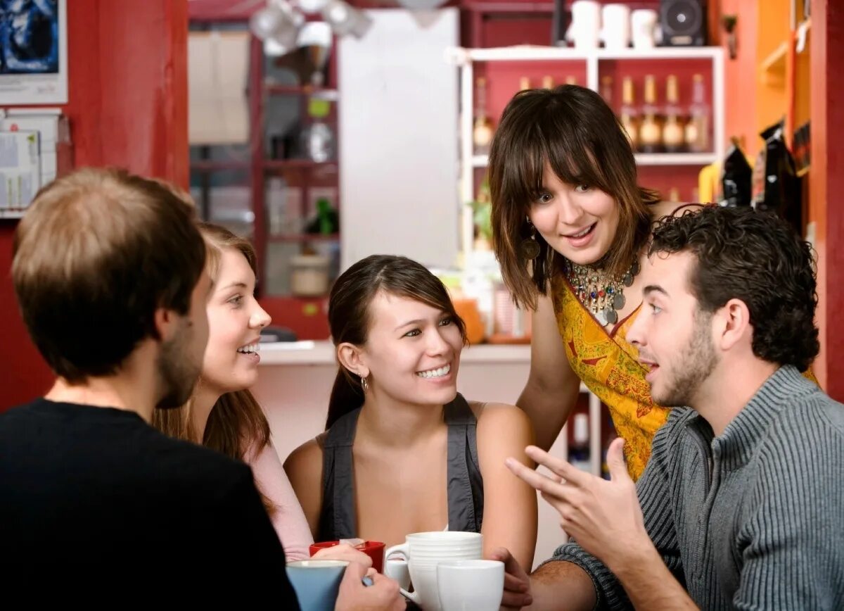 Люди делятся впечатлениями. Друзья и встречи. Разговоры с друзьями. Живое общение. Подростки за столом в кафе.