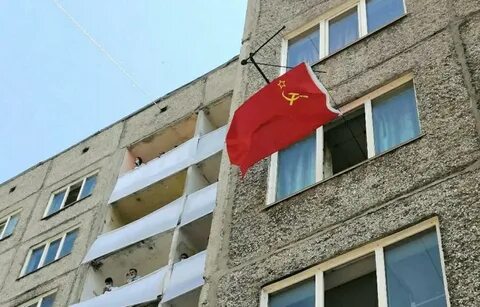 Вешает флаг на балконе