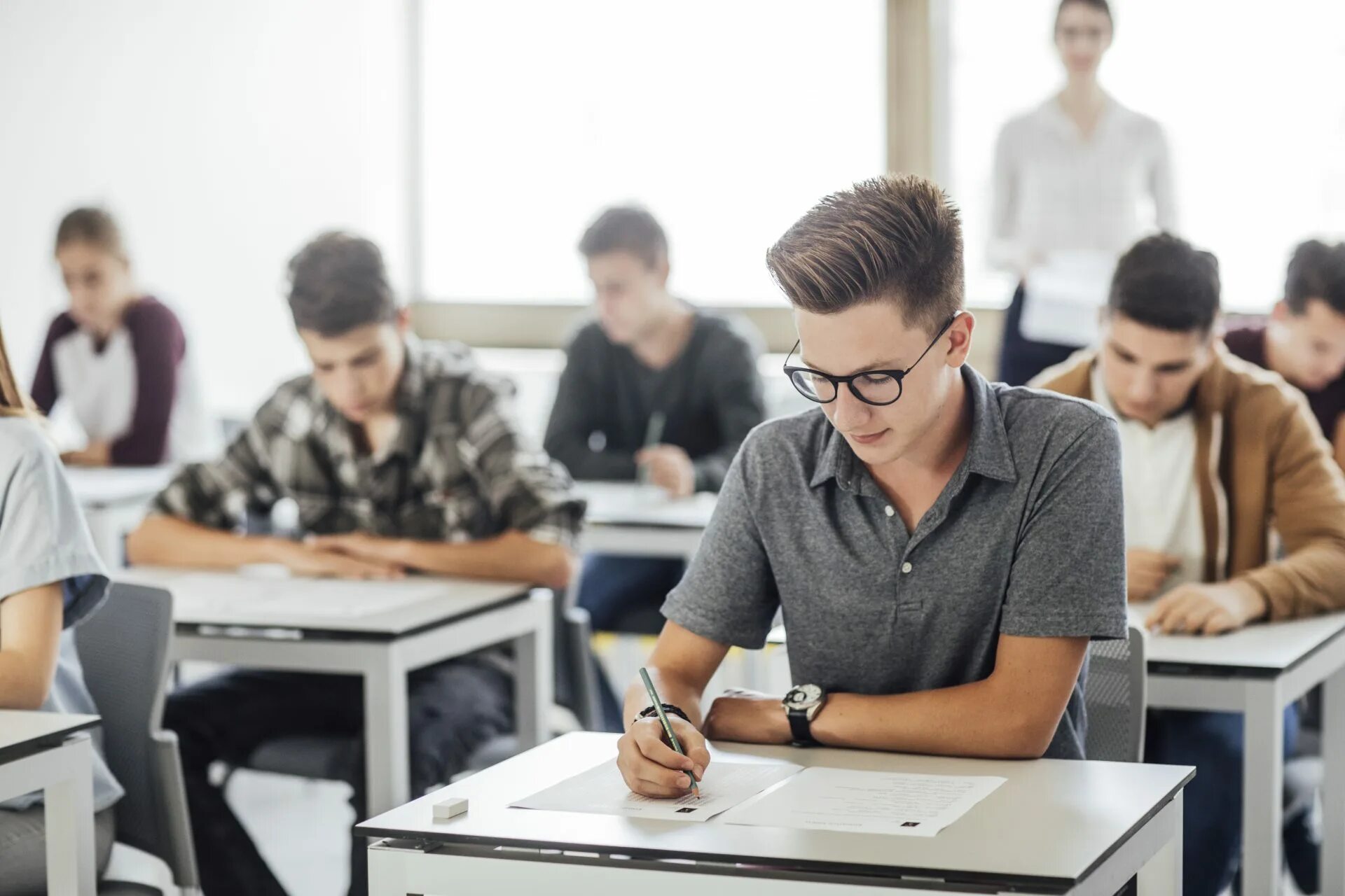 The teacher wants the students. Студент за партой. Студенты в аудитории. Учеба в вузе. Человек за партой.