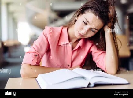 Female student studying and reading in a library but is having a hard time ...