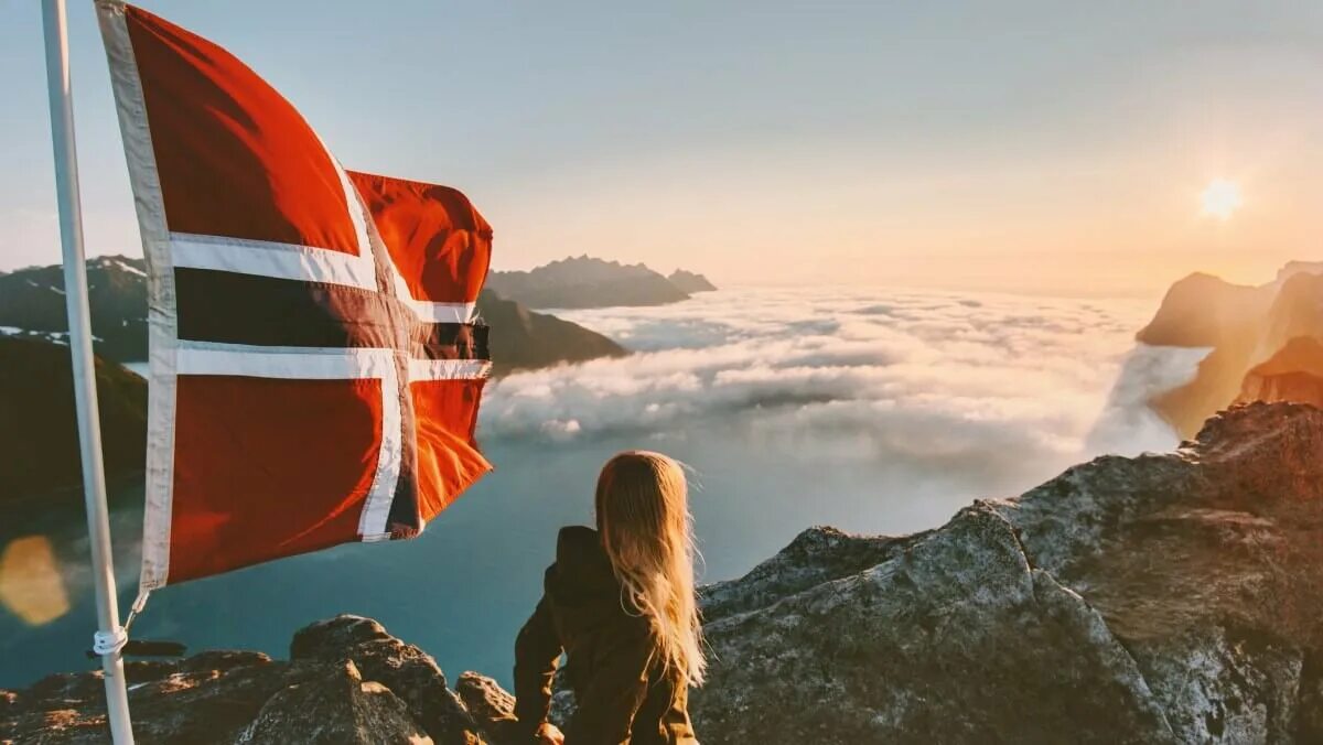 Путешествия образ жизни. Парень с флагом Норвегии. Девочка с флагом Норвегии. Девочка с флагом Норвегии на фоне реки. Образы для путешествий 2024.