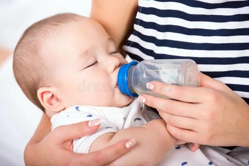 Искусственное вскармливание. Little-baby-drinking-water-from-bottle-indoors. Новорожденных надо поить водой. Младенец пьет воду. Малыш с бутылочкой.