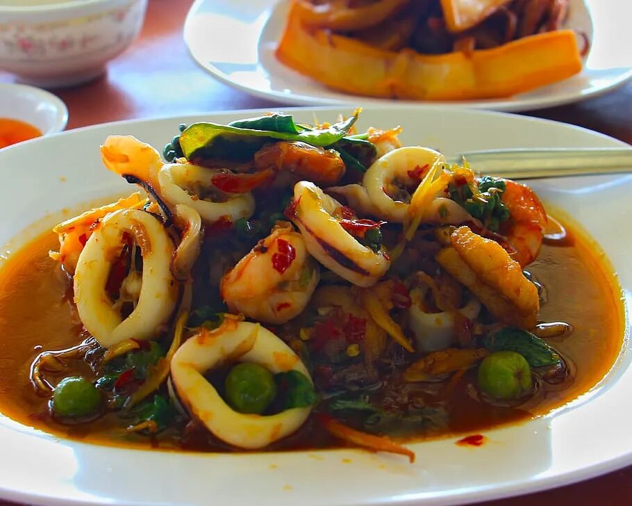 Кальмар с овощами на сковороде. Национальная кухня мадагаскара. жареный кальмар. жареный кальмар с овощами. китайский кальмар.