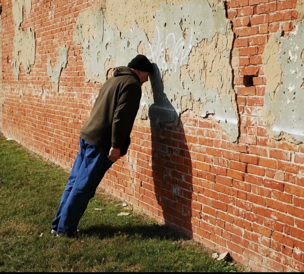 Головой об стену. Человек перед кирпичной стеной. Человек у стены. Человек уперся в стену. Неприятный биться