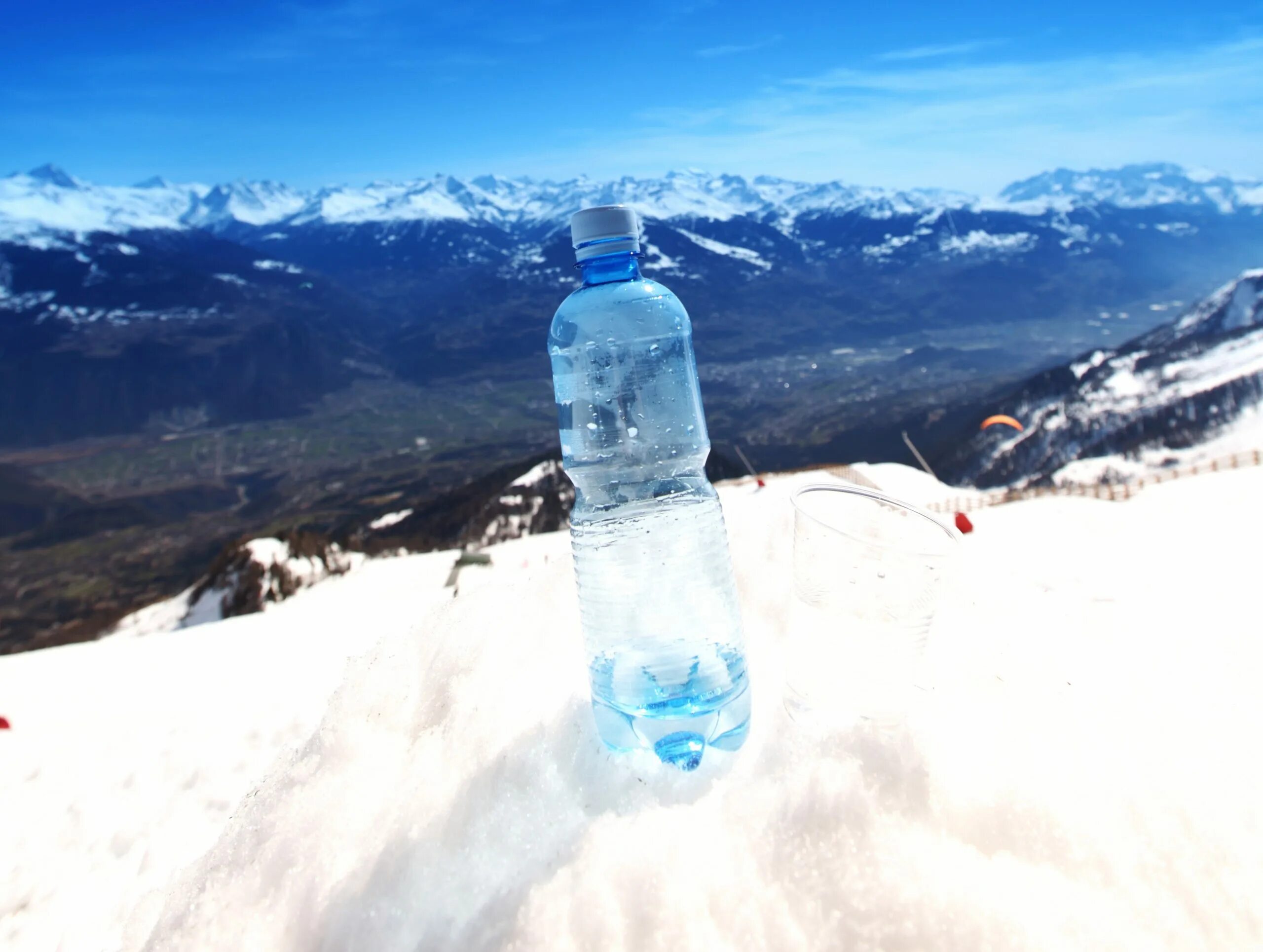 Замерзла вода в бутылке. Бутылка воды на фоне гор. Бутылка воды зима. Пить воду горы. Бутылка с водой зимой.