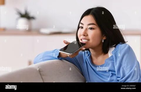 Download this stock image: Young asian woman using voice assistant on smart...