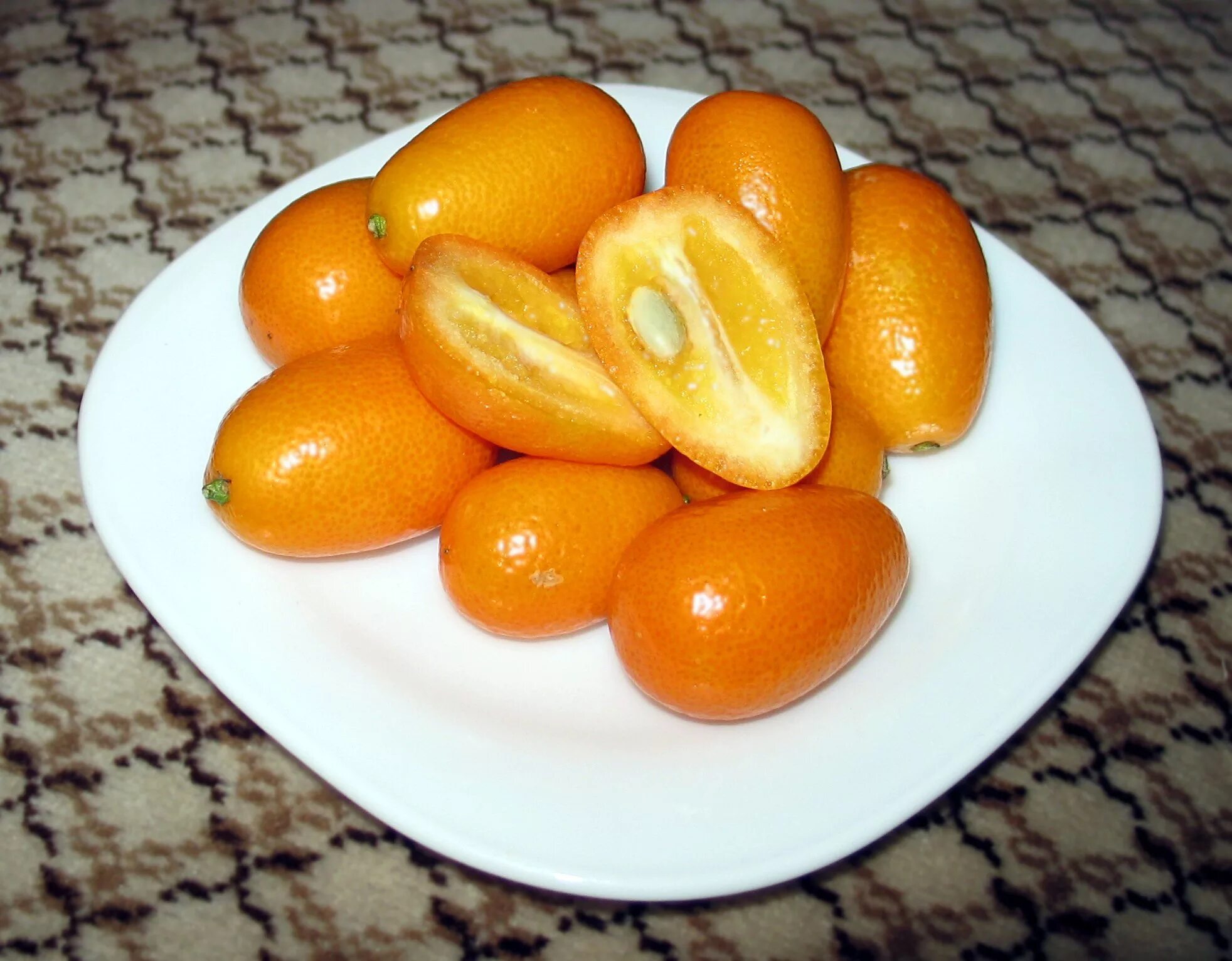 Оранжевый фрукт с черными. Дикий мандарин кумкват. Кумкват Маруми. Фрукт цитрус кумкват. Кинкан кумкват.