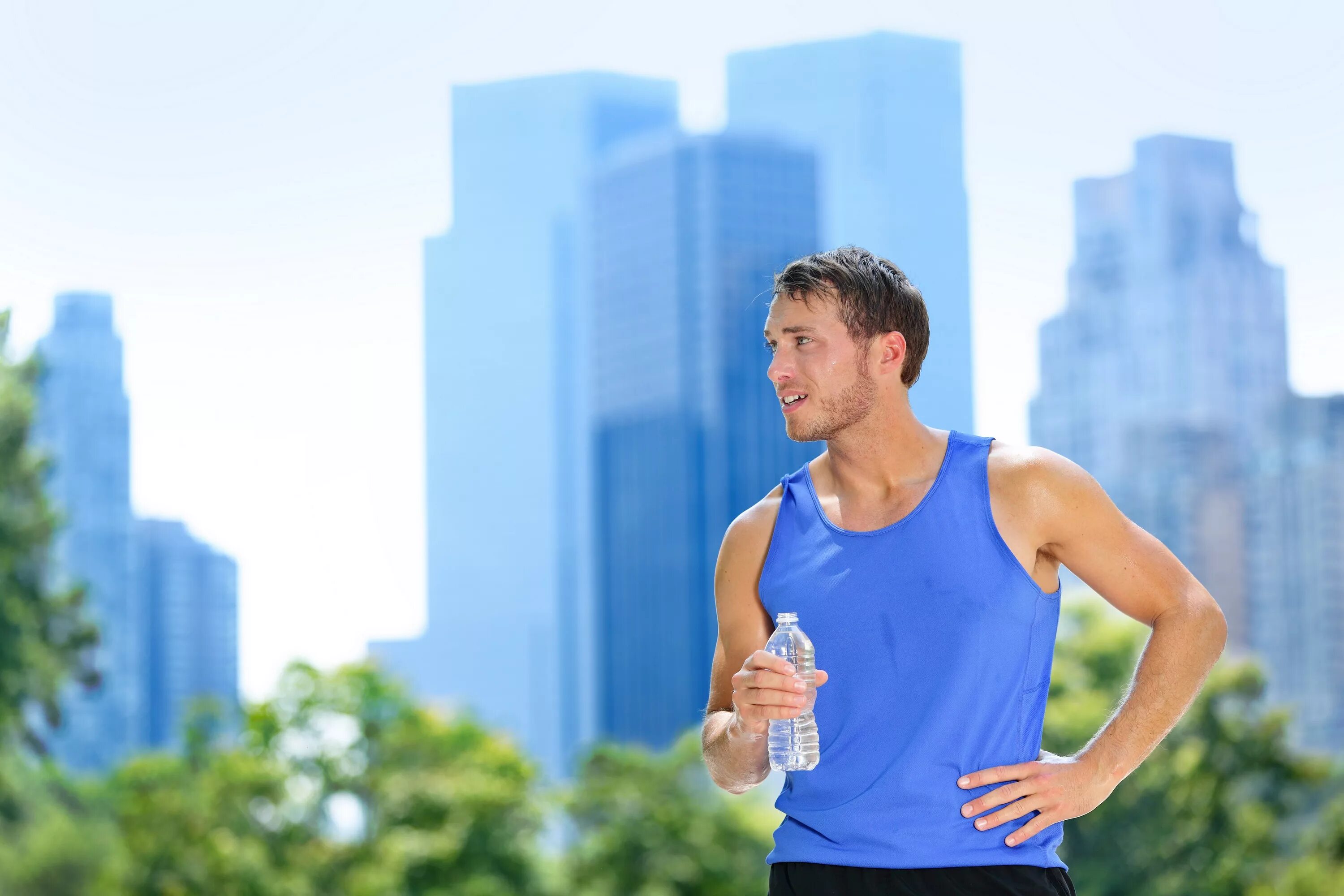 Спортсмен на улице. Заниматься спортом в жару. Спортивный мужчина пьет воду. Питьевой режим на пробежке.