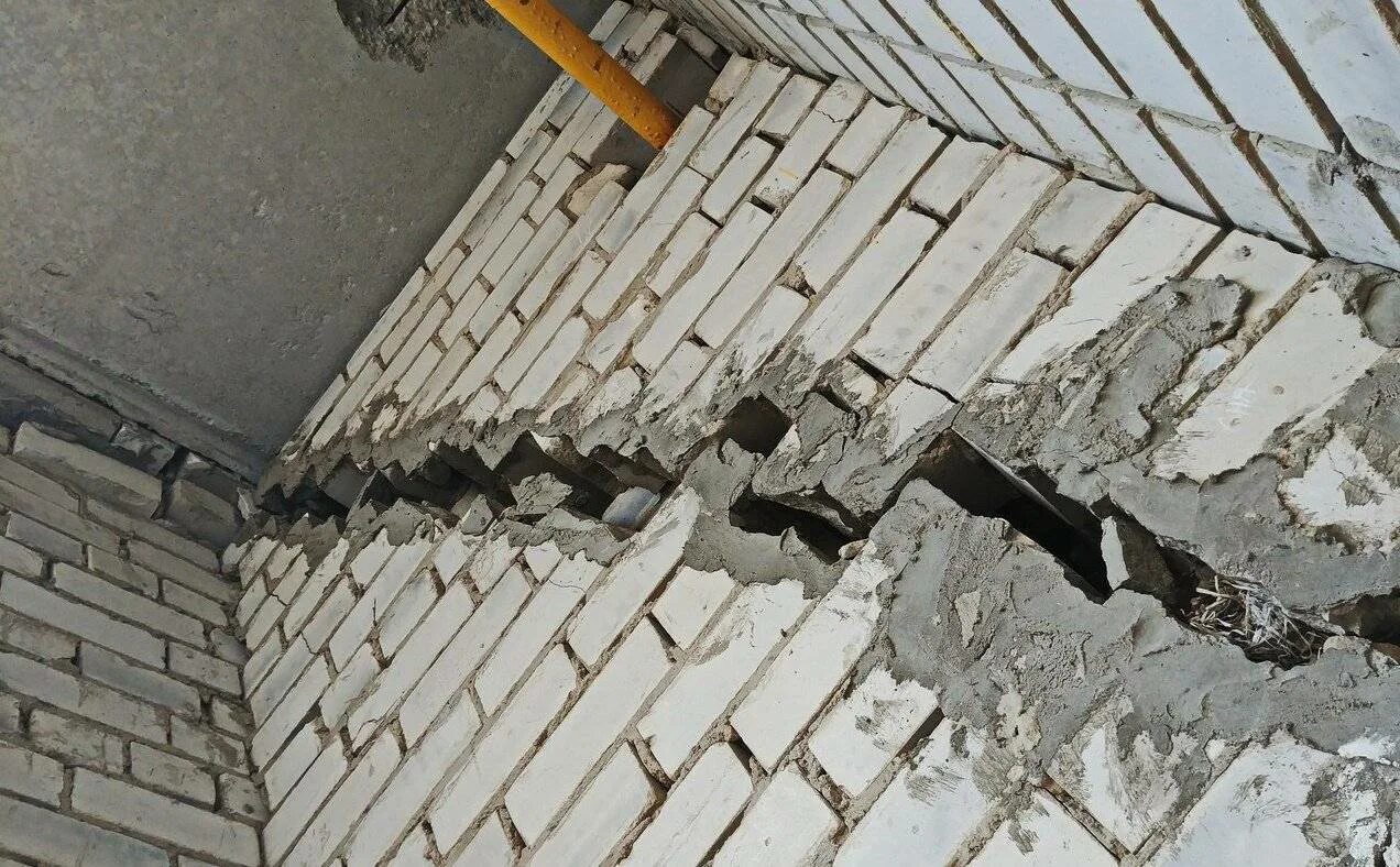 Трещина в многоэтажном доме. Разрушение строительных конструкций. Дефекты кирпичной кладки. Трещина в несущей стене.
