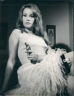 Claudine Auger with feathers and a gun.