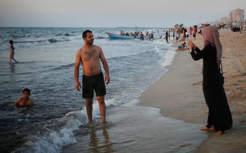 Мусульманский пляж. Купаются на пляже. Мужчины мусульмане на пляже. Арабские женщины купаются в море.
