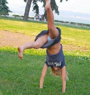 Handstand in a skirt : Girls Gymnasts Perform Acrobatic Elements On A Green...
