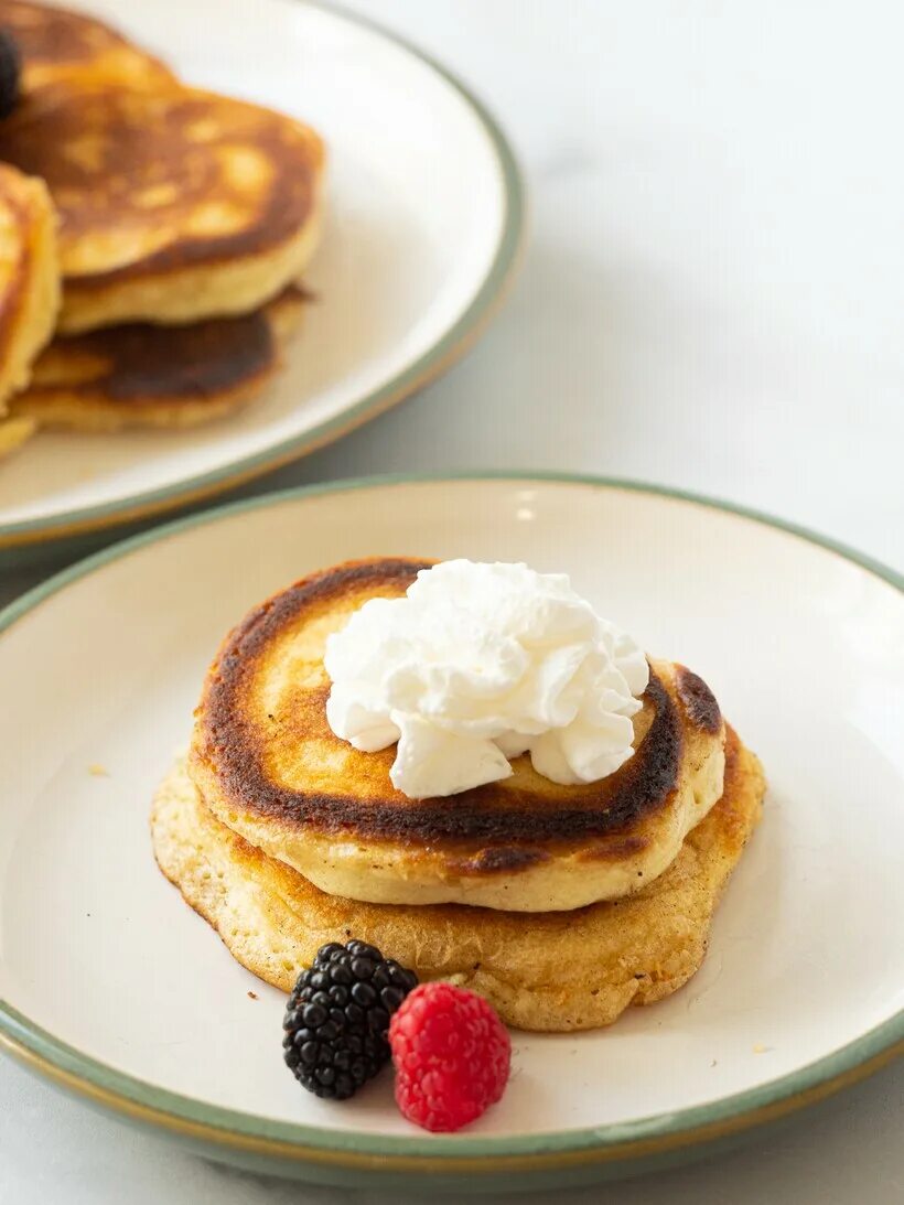 Оладьи со сметаной. Две оладьи. Оладьи на кукурузной муке и сметане. Шоколадные оладушки. Сырники на белой тарелке.