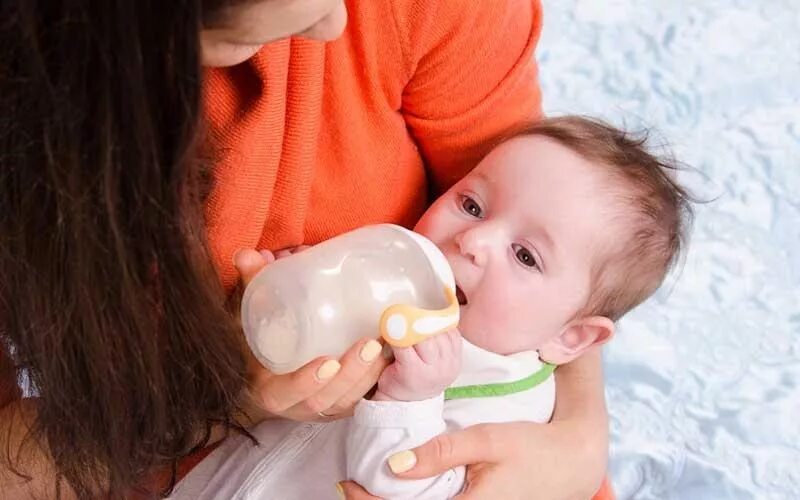 Молоко мамаши. Ребенок ест из бутылочки. Кормление из бутылочки новорожденного. Дети с лактазной недостаточностью. Малыш пьёт молоко у мамы.
