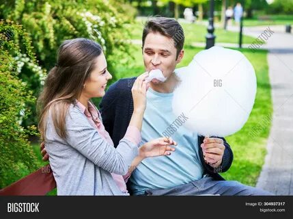 Download high-quality Young couple strolling park eating cotton candy image...