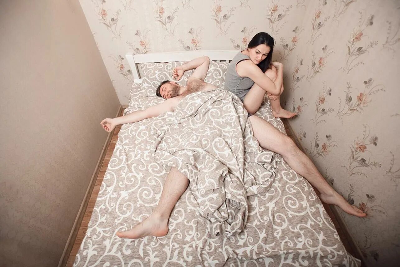 Семейная пара в спальне. Мужчина занимает всю кровать. Девушка заняла всю кровать. Женщина на всю кровать.