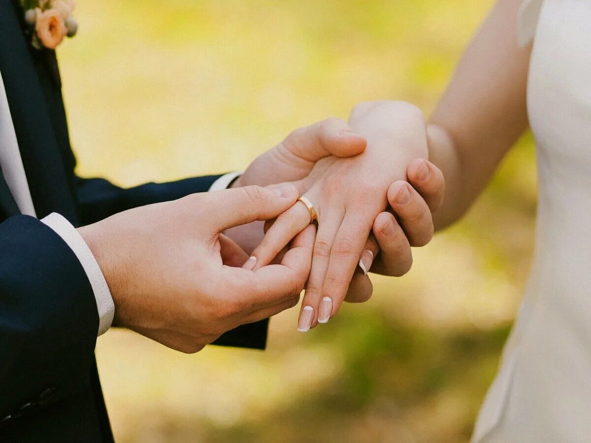 Свадебные пары. Жених надевает кольцо невесте. Жених и невеста держатся за руки. Свадебные кольца на руках.