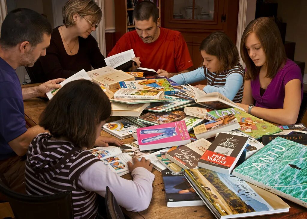 Читающая семья. Дети и родители в библиотеке. Творческое чтение. Семья читает книгу. Чтение в кругу семьи.